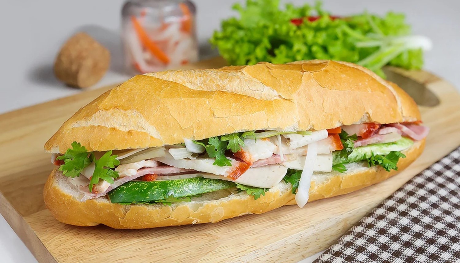 Ổ bánh mì đặc biệt Sài Gòn được cắt đôi để lộ các lớp nhân phong phú: pâté, chả lụa, dưa chua và rau mùi