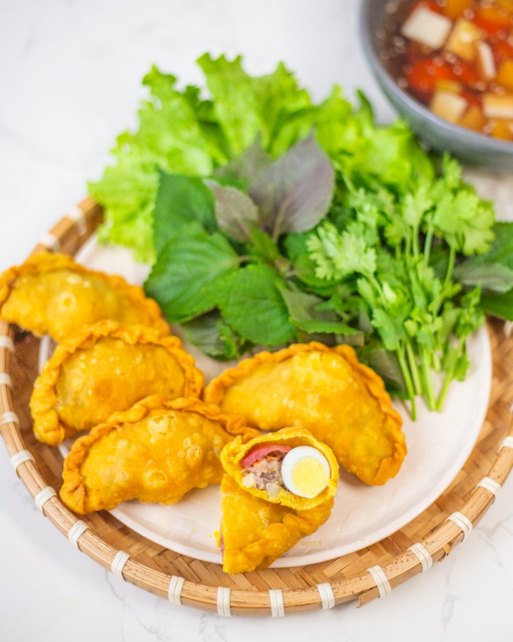 Bánh gối Hà Nội vàng giòn vừa vớt ra khỏi chảo dầu, xếp ngay ngắn trên rổ và đĩa nước chấm chua ngọt bên cạnh