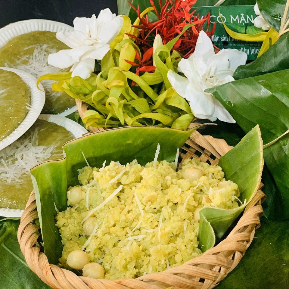 Gói cốm lá sen xanh mướt từ làng Vòng bày trên đĩa — màu xanh ngọc tự nhiên và mùi thơm lúa non đặc trưng của mùa thu Hà Nội