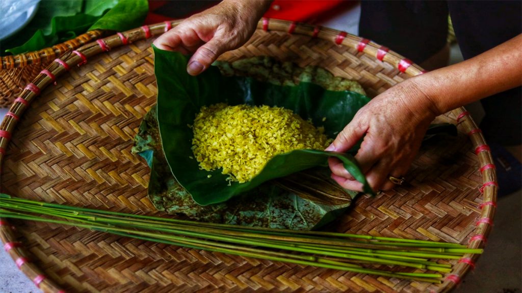 Người làng Vòng đang giã cốm trong cối đá thủ công vào buổi sáng sớm mùa thu — động tác giã nhịp nhàng truyền thống qua nhiều thế hệ
