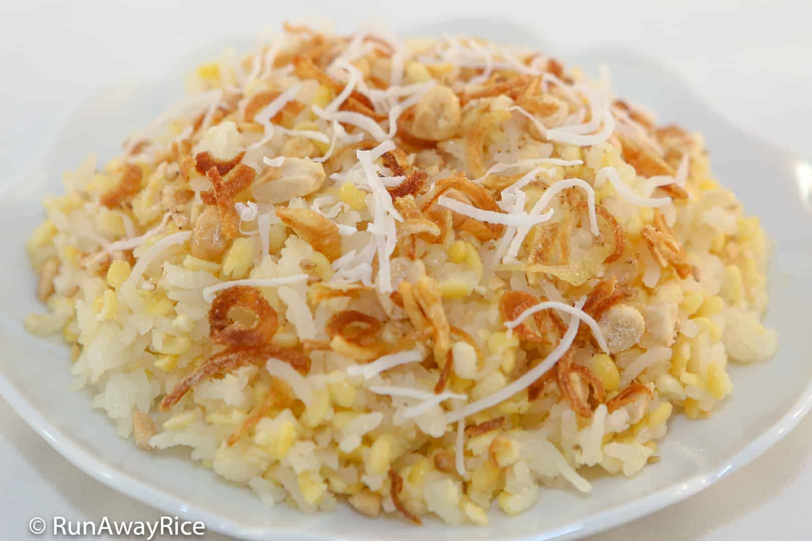 Người bán xôi xéo Hà Nội đang rưới mỡ hành thơm lên đĩa xôi phủ đậu xanh vàng cho khách hàng đang chờ