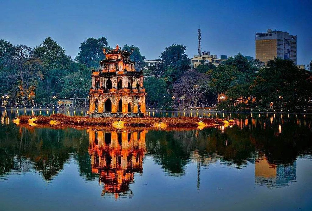 Cầu Thê Húc đỏ thắm cong vút dẫn đến Đền Ngọc Sơn trên đảo giữa Hồ Hoàn Kiếm buổi sáng sớm trong sương mù Hà Nội