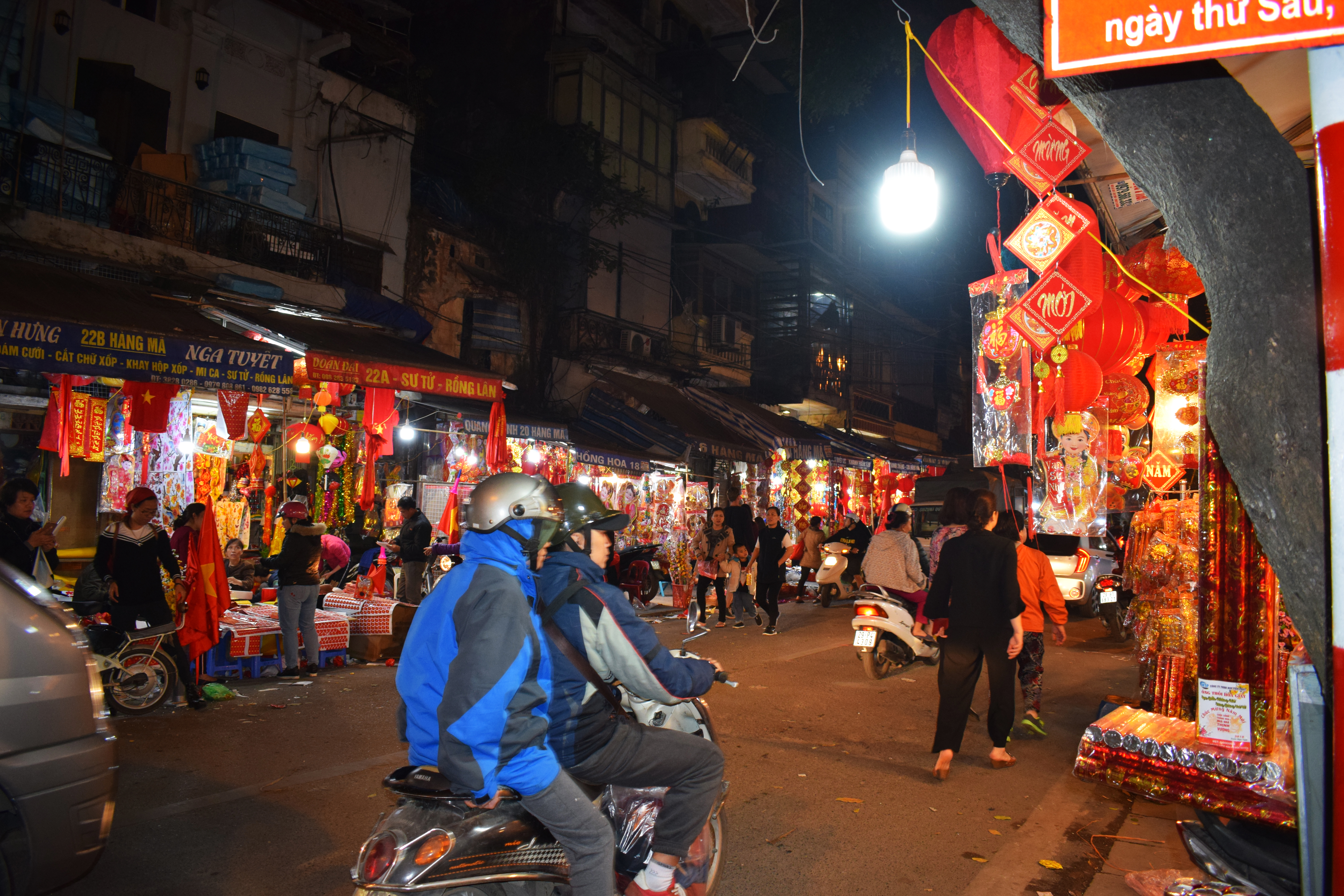 Phố cổ Hà Nội về tối với ánh đèn vàng và dòng người qua lại trên đường phố hẹp