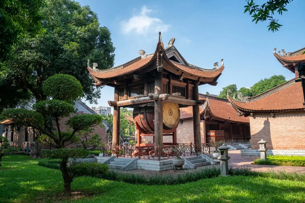Sân vườn yên tĩnh trong khuôn viên Văn Miếu với cây xanh cổ thụ và kiến trúc gỗ cổ điển — một ốc đảo bình yên giữa lòng Hà Nội